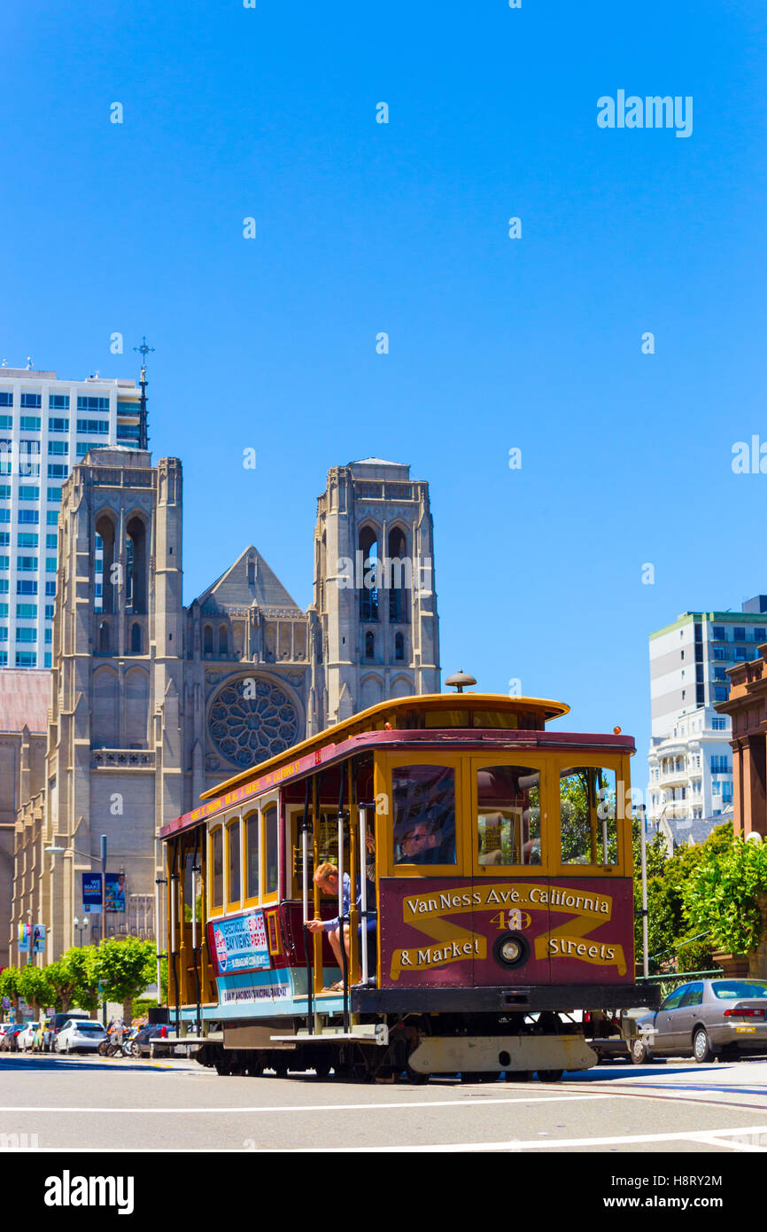 Cable car passing down California Street in front of Grace Cathedral on top of Nob Hill. Vertical Stock Photo