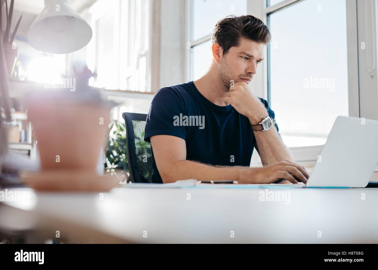 Handsome young man using laptop. Businessman browsing internet on his laptop. Stock Photo