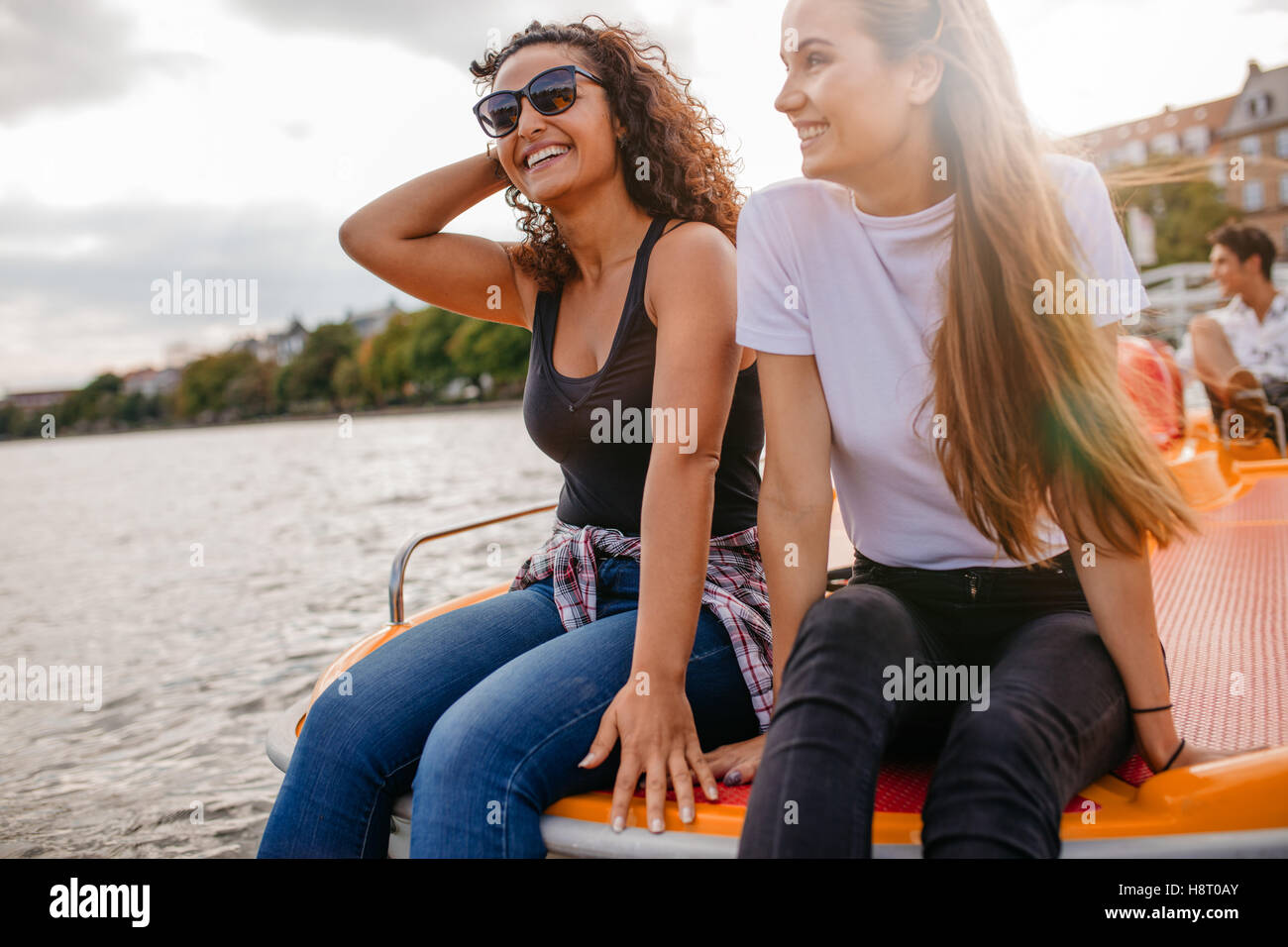 Outdoors Shot Of Two Female Friends Sitting In Front Pedal Boat