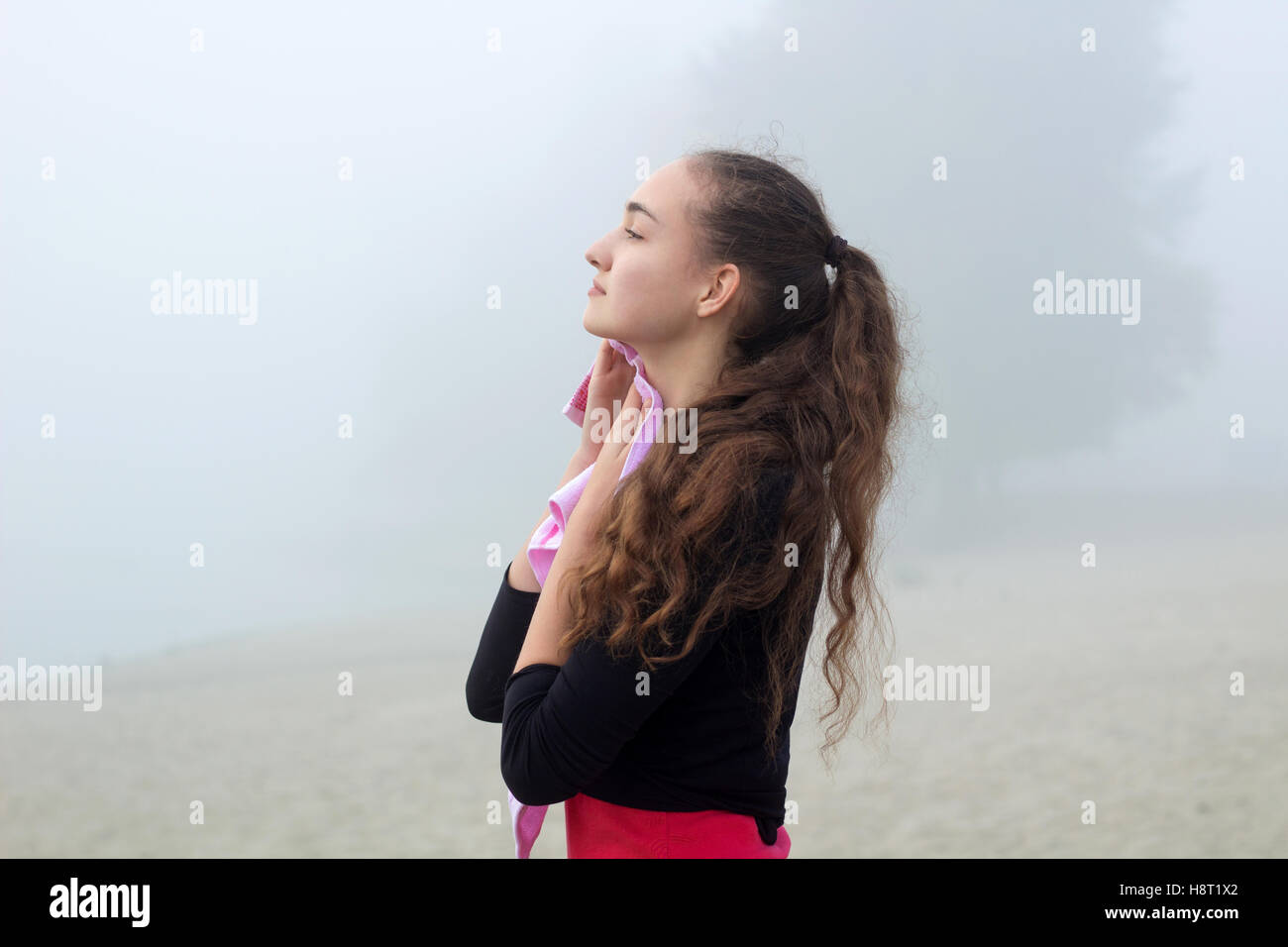 Young pretty slim fitness sporty woman with towel during break at training workout outdoor Stock Photo