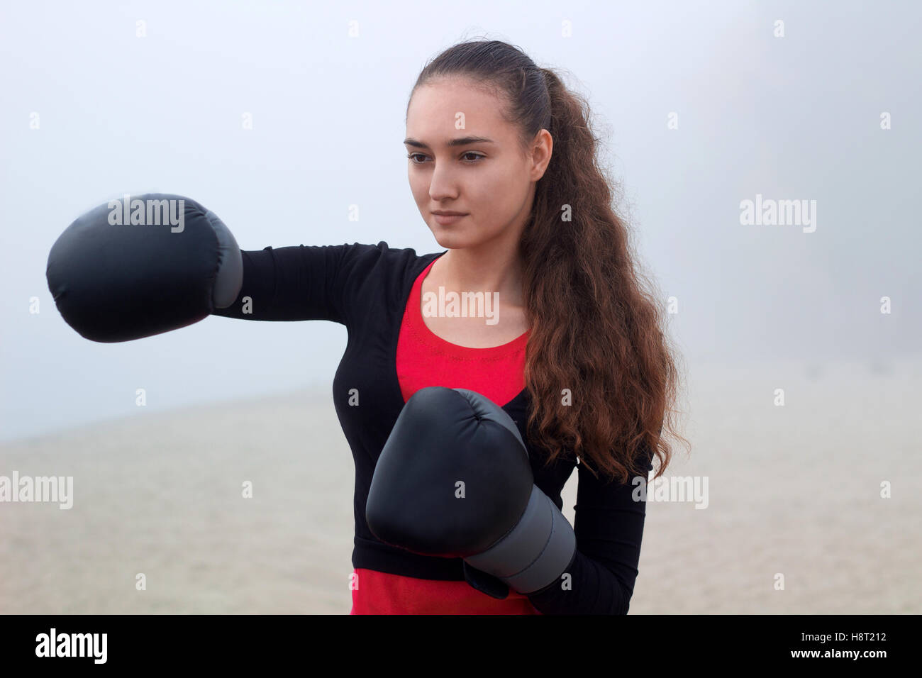 Young pretty slim fitness sporty woman does boxing exercises during training workout outdoor Stock Photo