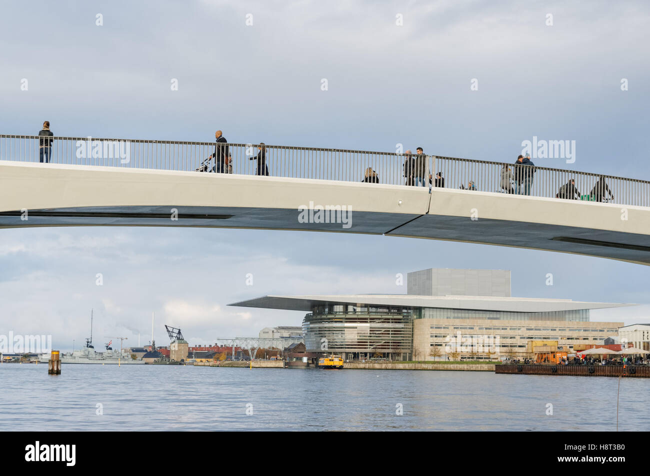 People on Inderhavnsbroen pedestrian and cyclist bridge with Copenhagen Opera House Operaen in the background, Copenhagen, Denmark Stock Photo