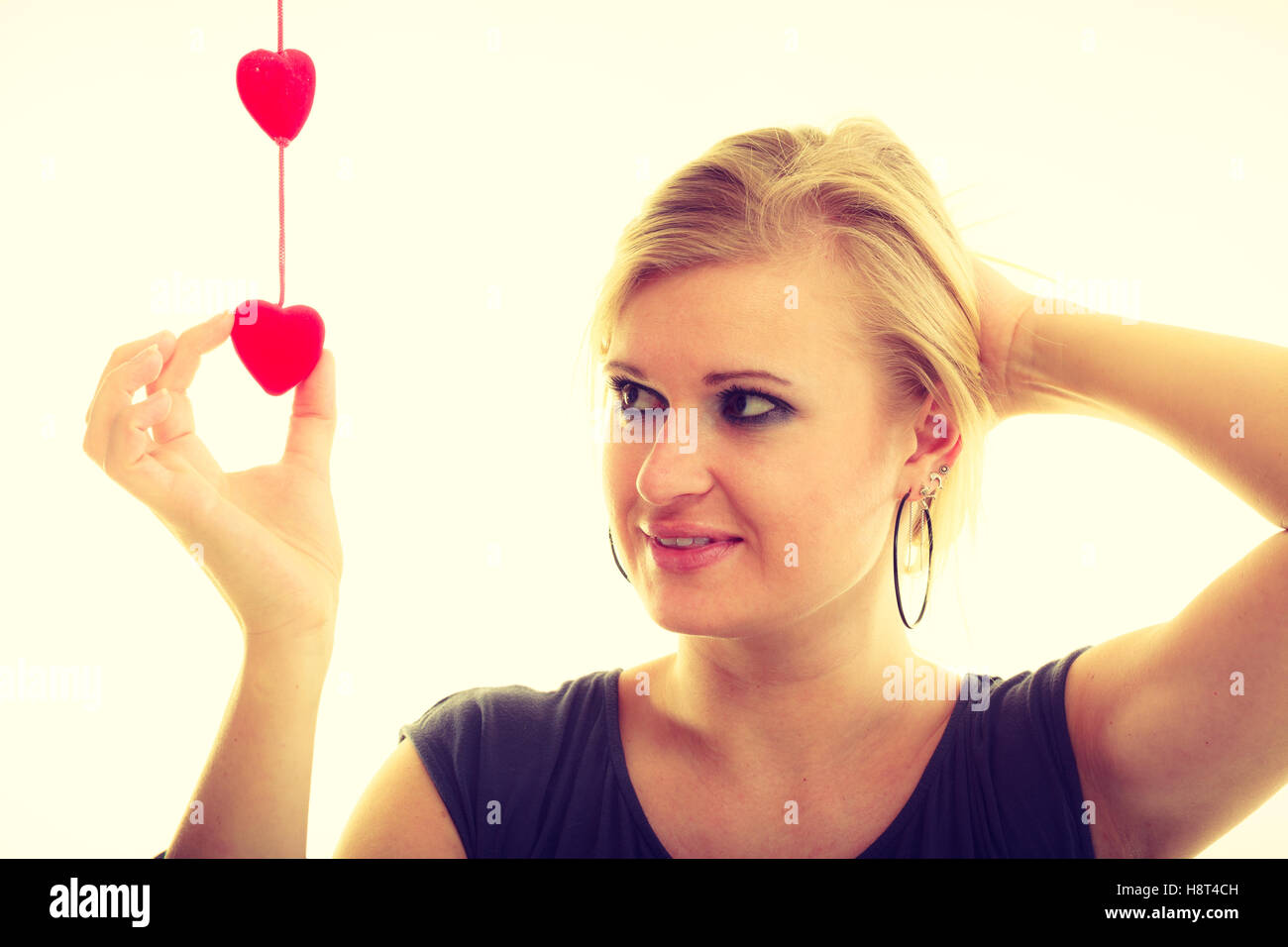 Falling in love concept. Enamoured female lover with little small red hearts. Blonde attractive woman full of positive emotions Stock Photo