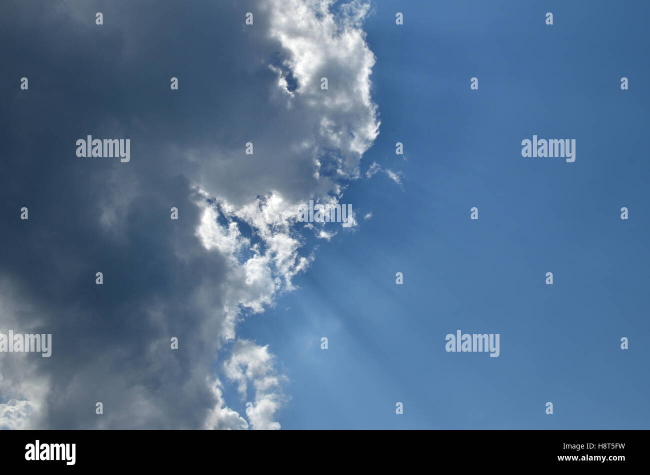 Sunbeams behind cloud on clear blue sky Stock Photo - Alamy