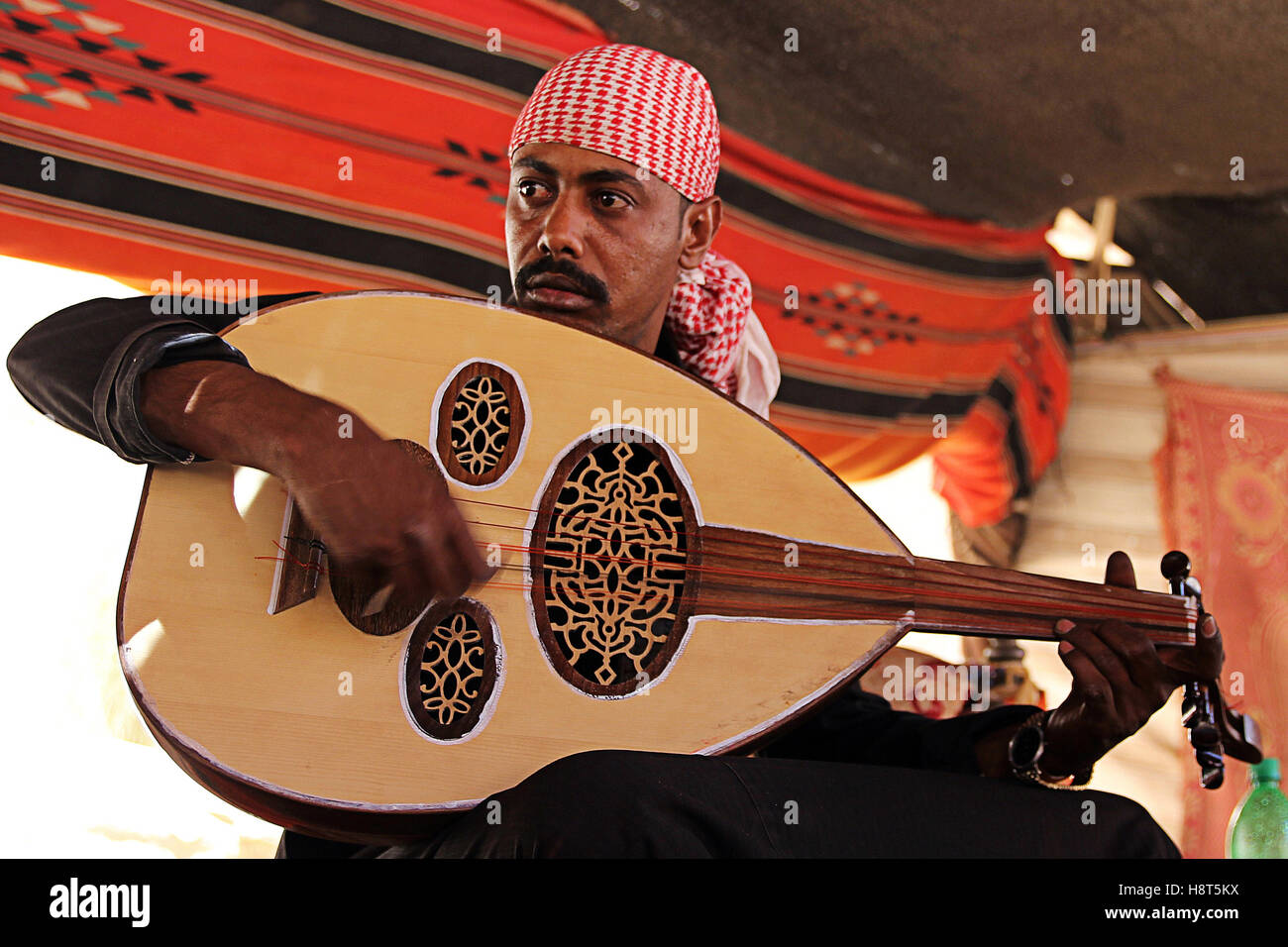 Bedouin playing guitar in tent, Valley of Wadi Rum, desert in Jordan Stock Photo