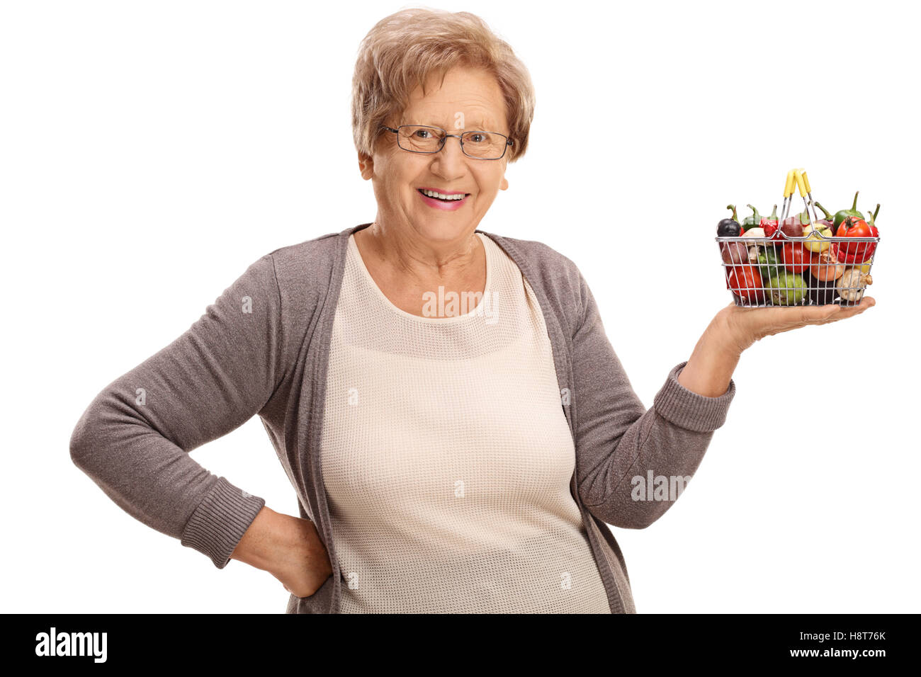 Happy elderly woman holding a small shopping basket full of fruits and ...