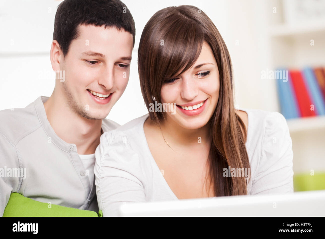 Portrait of a happy couple using their laptop in the living room. Stock Photo
