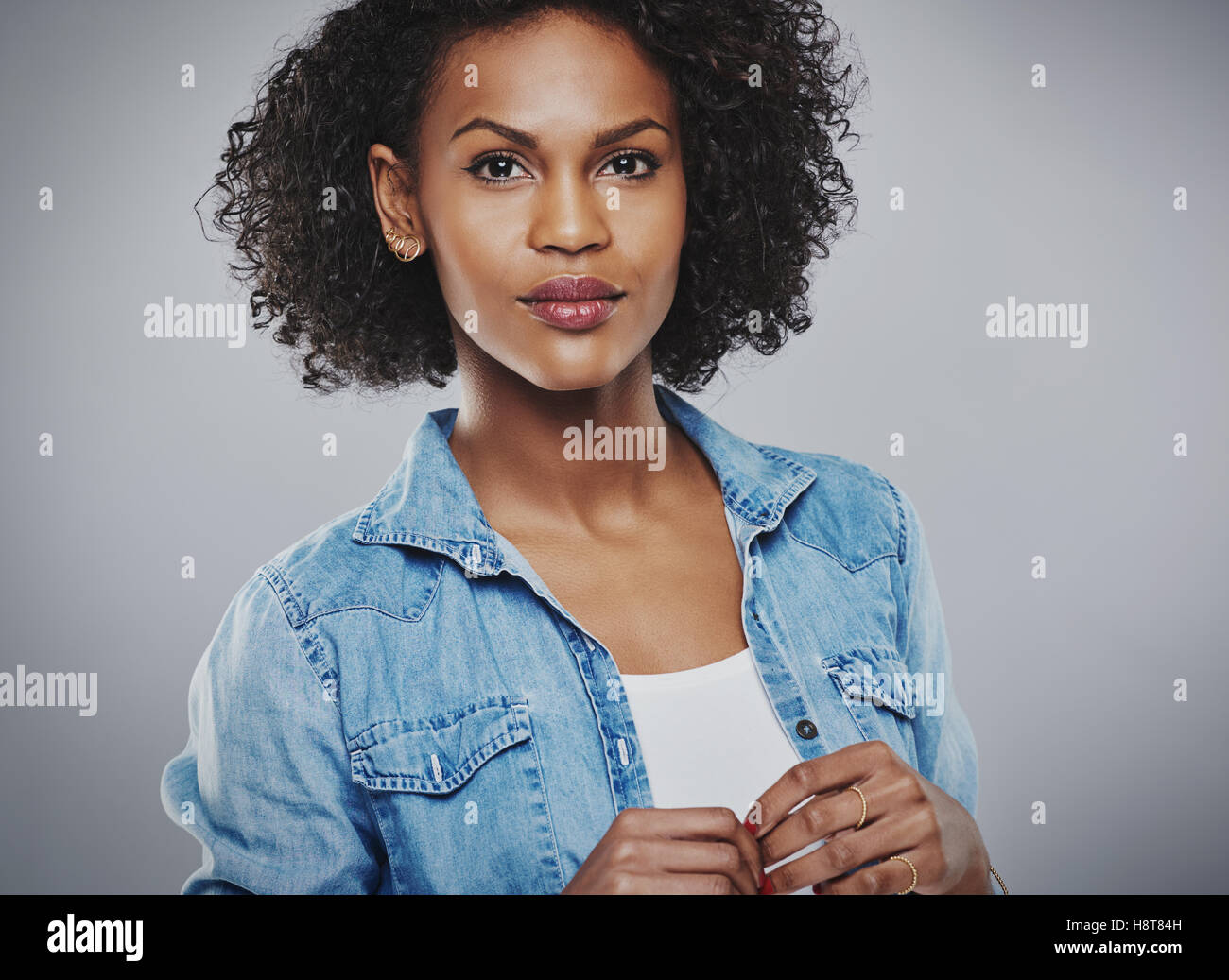 Serene woman with blue jean shirt and white top on gray background Stock Photo
