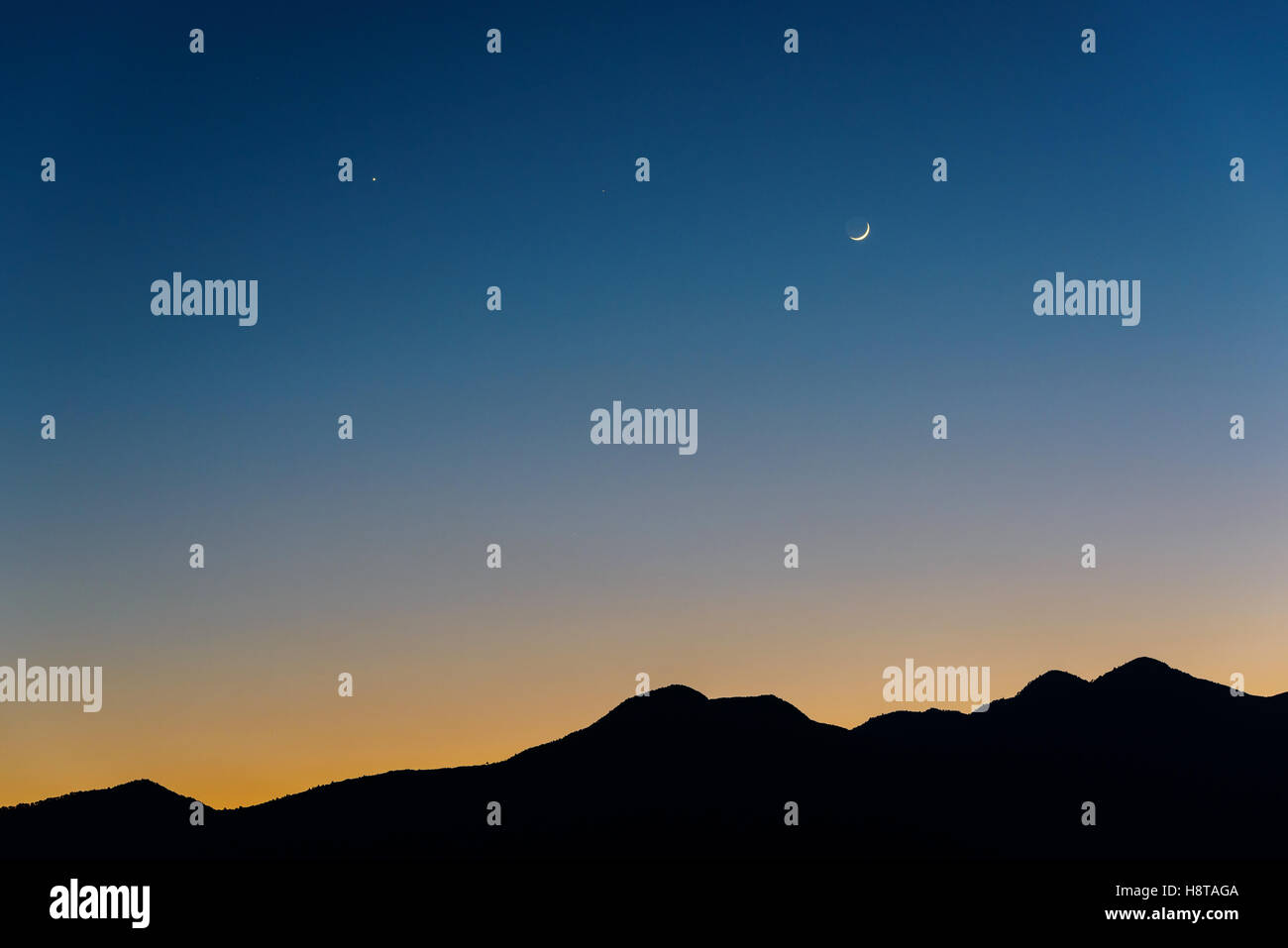 Waxing crescent Moon, Venus (left) and Saturn (middle) at dusk. Silhouette of mountains near Kathmandu in Nepal. Stock Photo