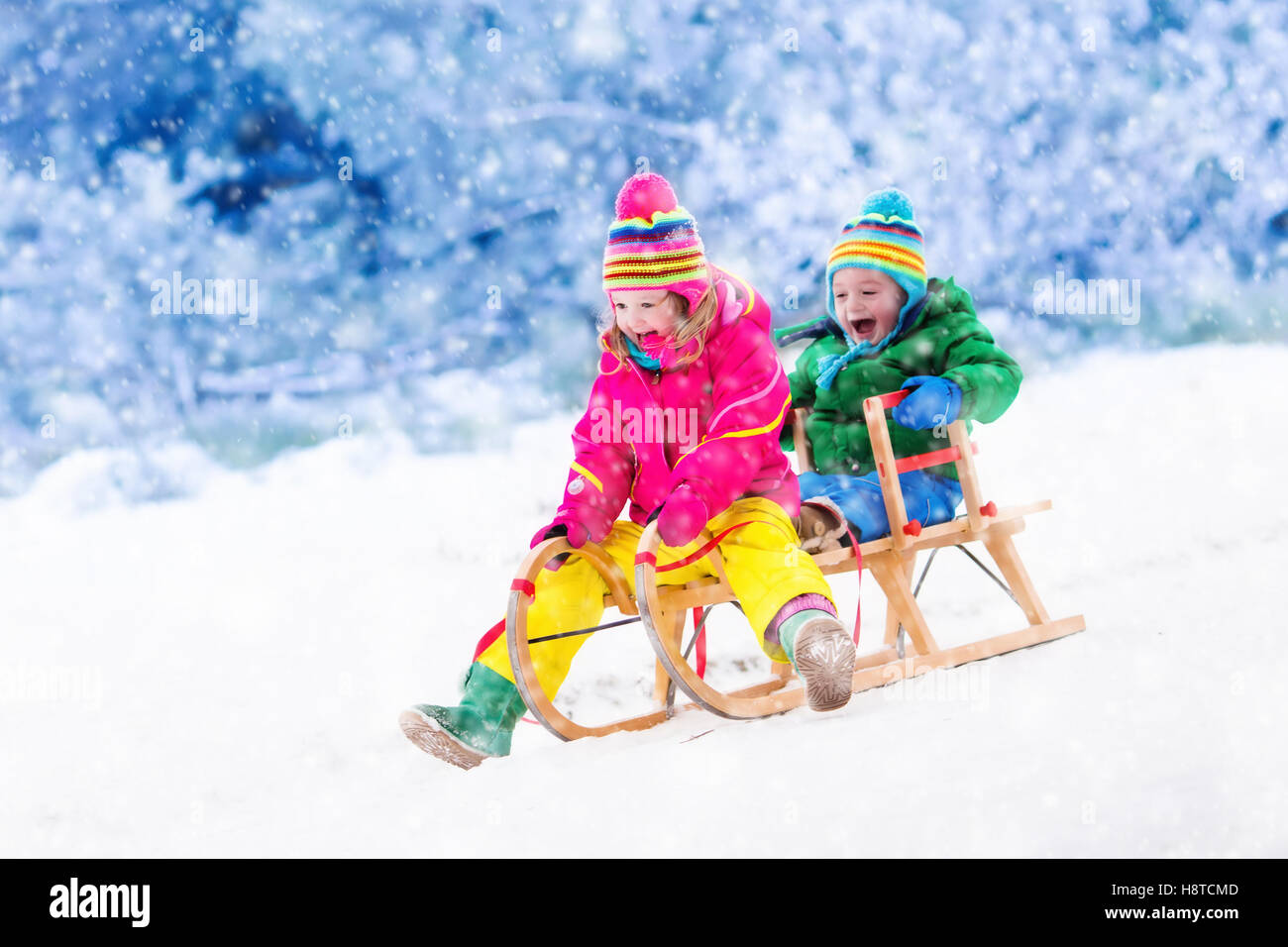 Little girl and boy enjoying sleigh ride. Child sledding. Toddler kid ...