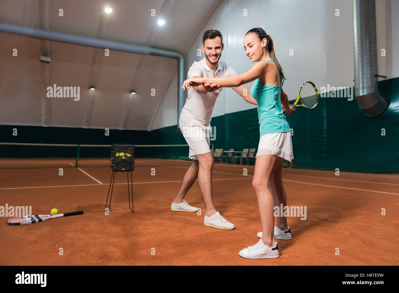 Professional delighted instructor teaching woman to play tennis Stock