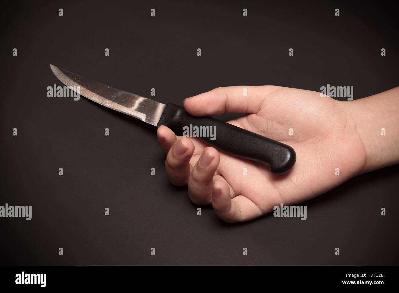 A sharp kitchen knife on somebody's hand. This image was shot with single flash light bouncing technique. Stock Photo