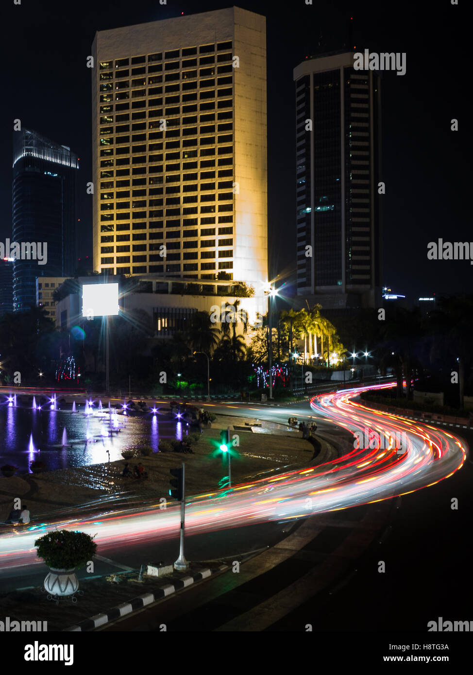 Light trails from vehicles traffic on the street at Bundaran HI, Thamrin, Jakarta downtown area at night. Stock Photo