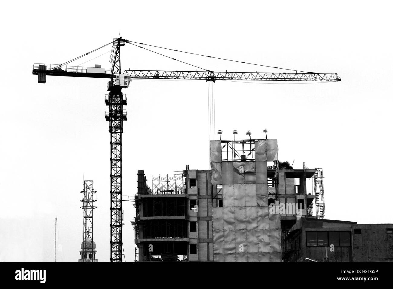 Crane tower over a construction building. Black and white photography