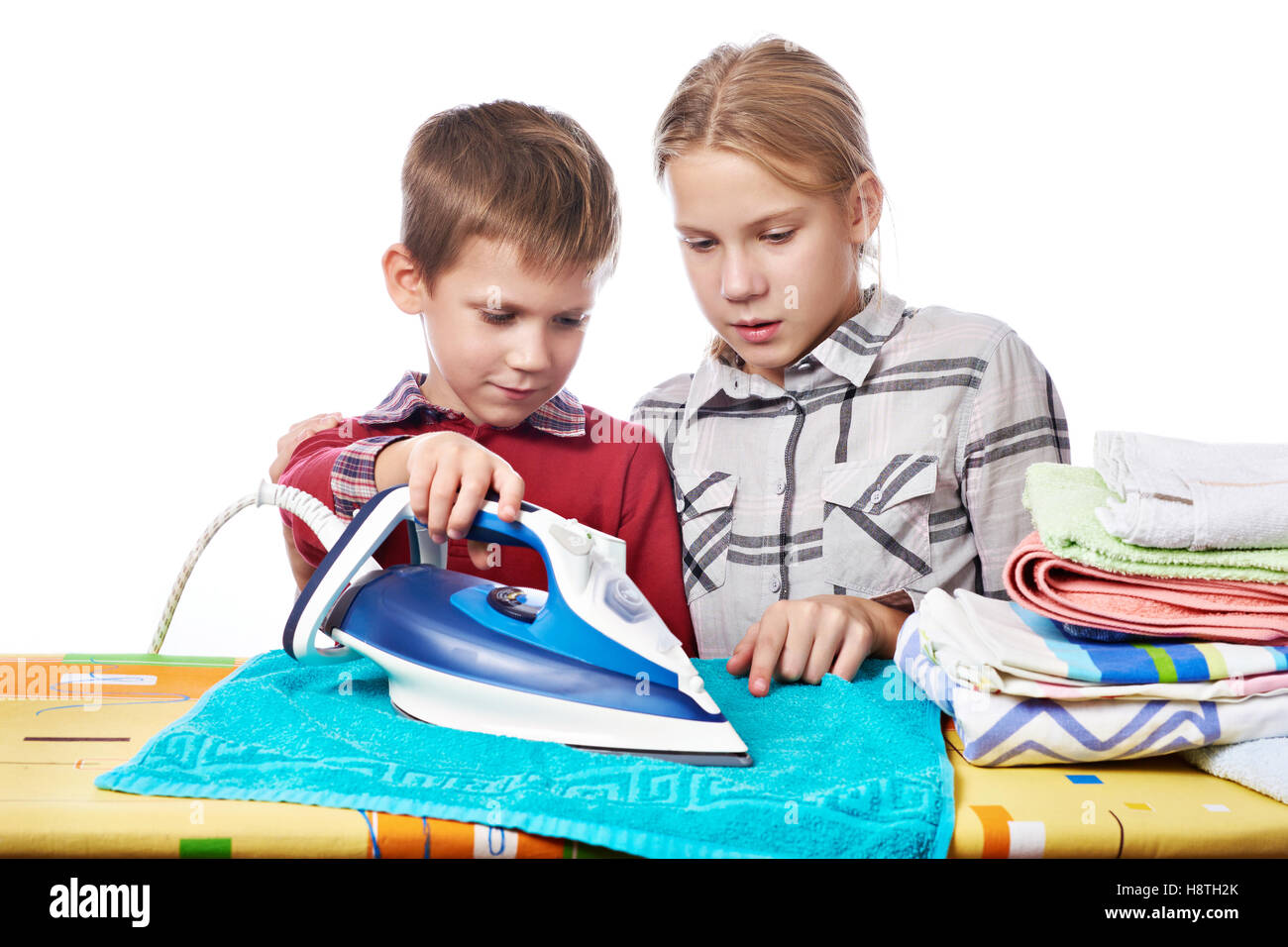 Sister helps younger brother to properly handle iron isolated white Stock Photo