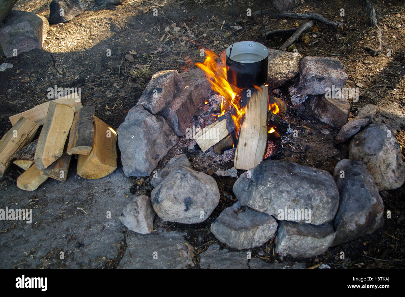 Preparing food on campfire in pot, wild camping Stock Photo - Alamy