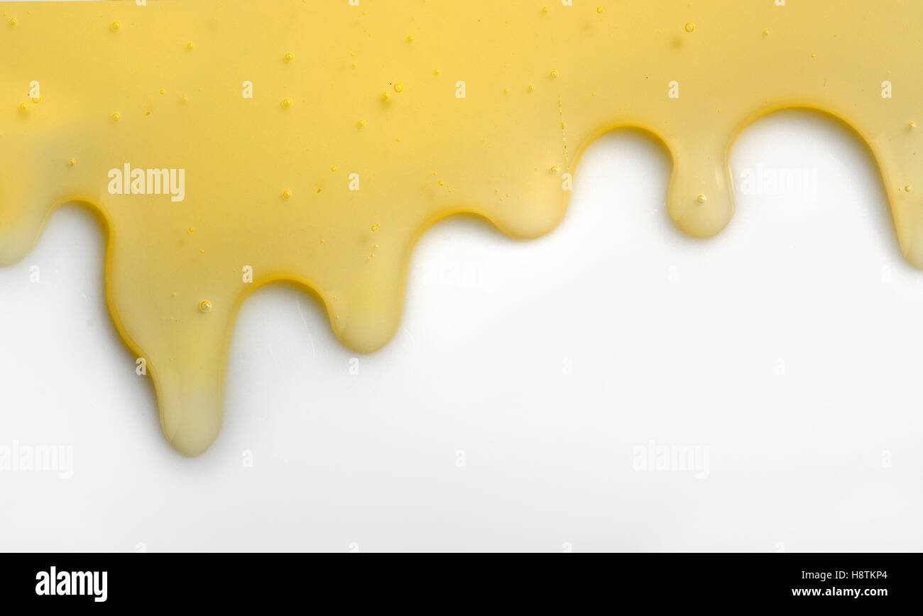 Honey liqiud flowing down on white table Stock Photo