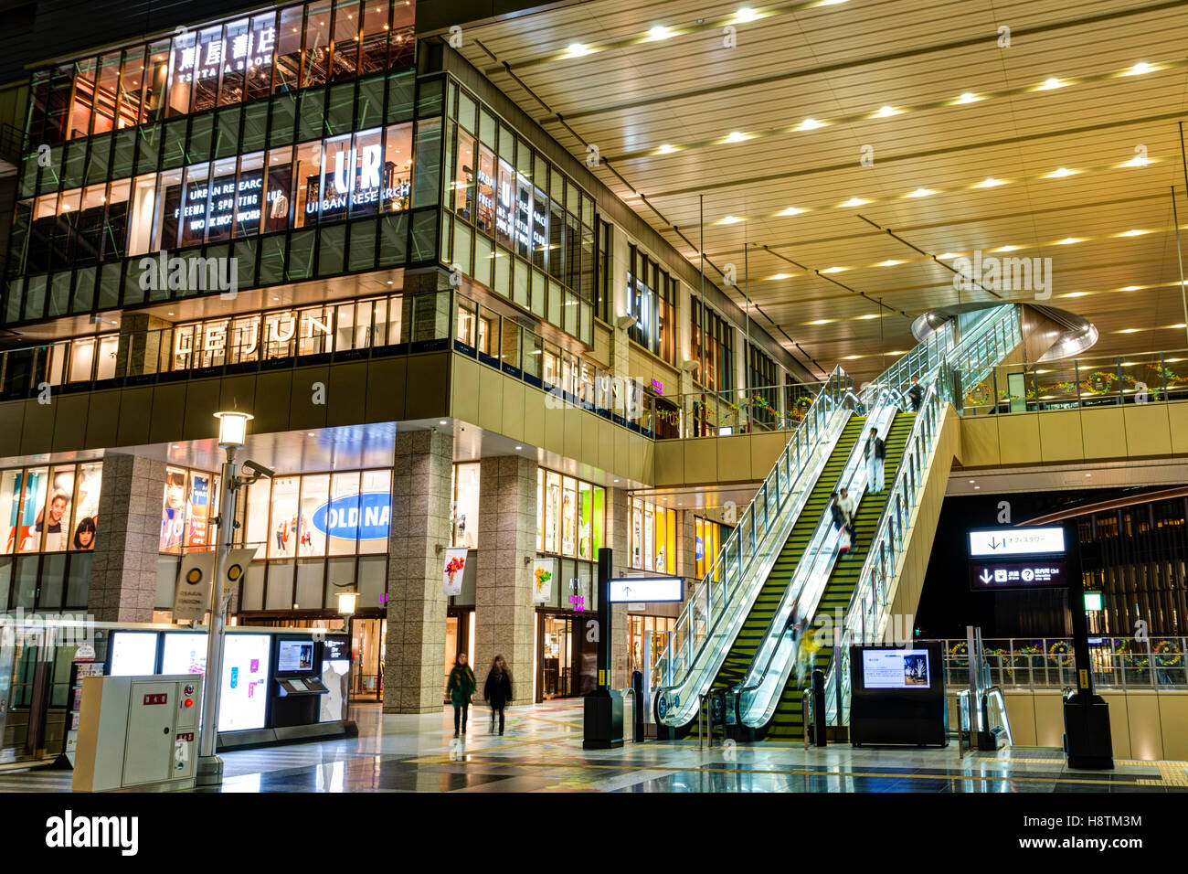Japan, Osaka Station City interior. North Gate Building entrance area with Lucua store, stairs and escalators to next level. Night time. People. Stock Photo
