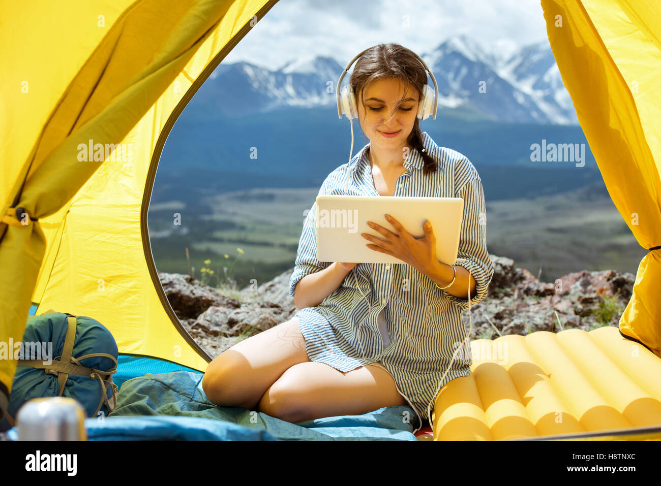 Beautiful girl tablet computer mountains headphones tent Stock Photo