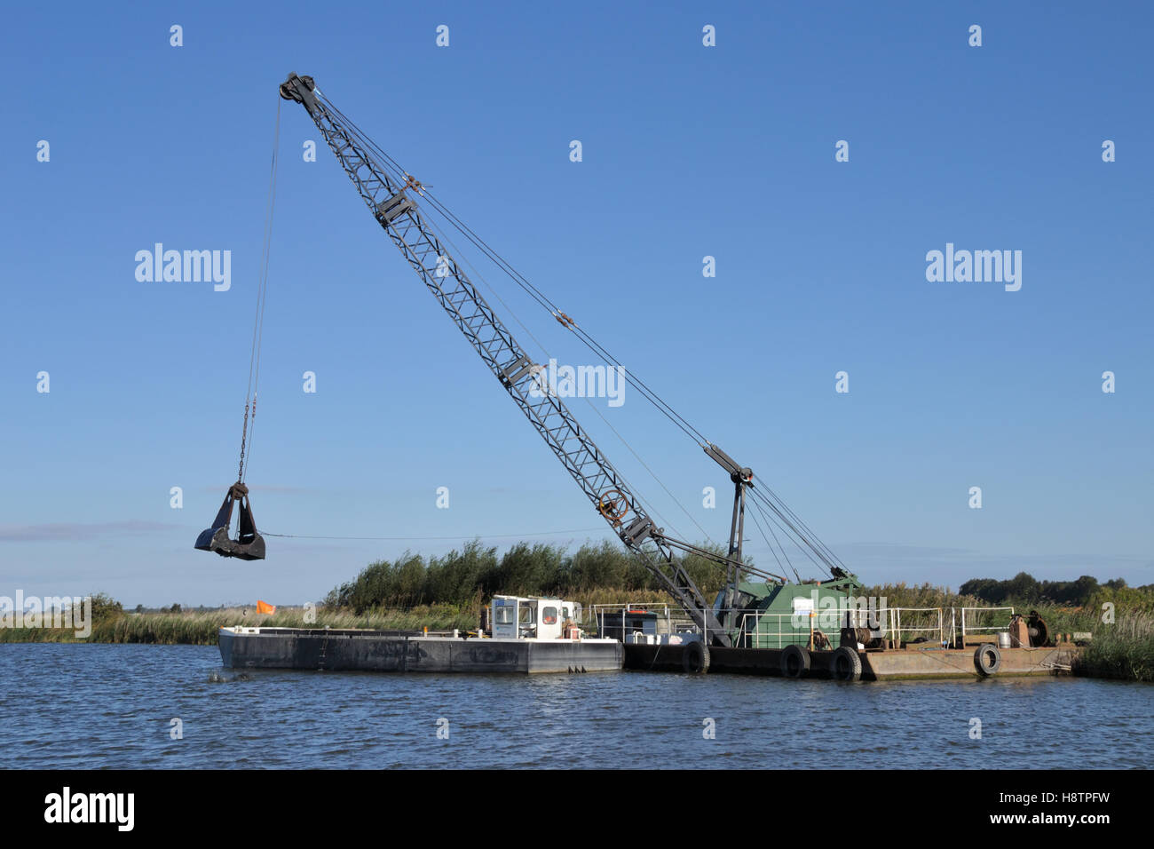 The Broads Authority using an excavator crane to dredge the River Bure on the Norfolk Broads Stock Photo
