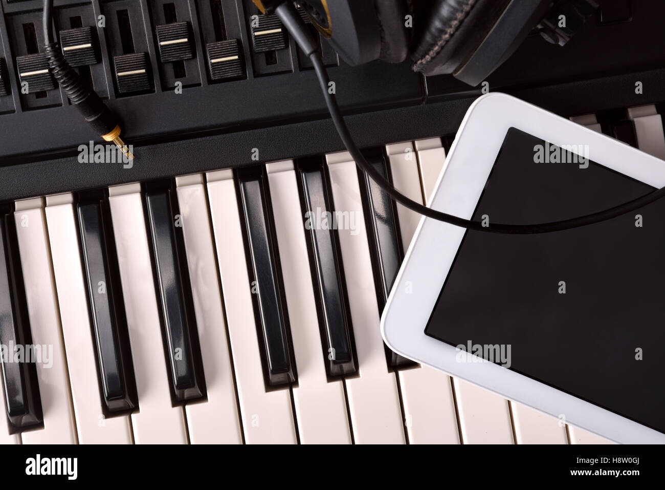 Electronic piano with headphones and tablet in studio recording