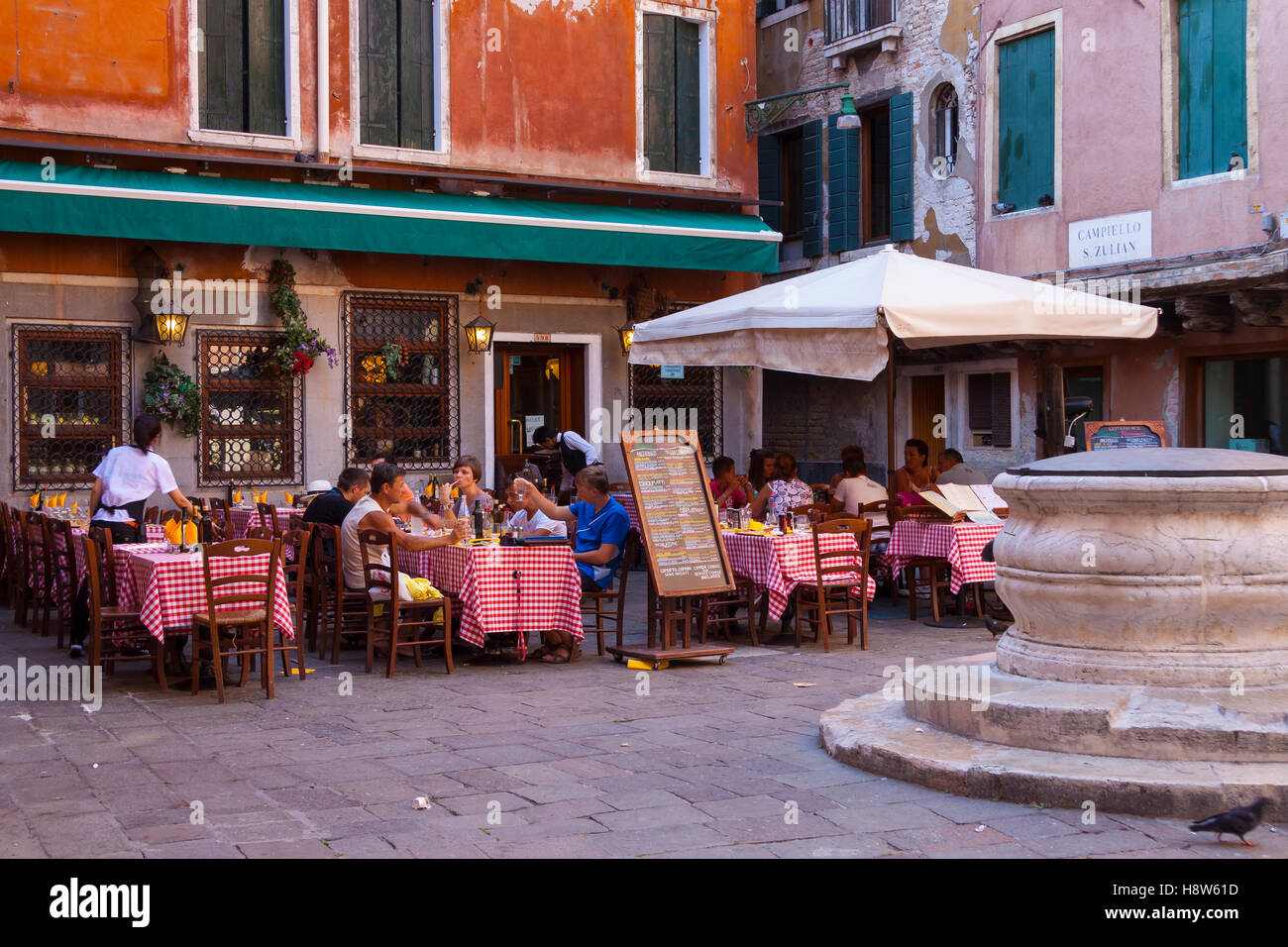 A Cafe' in an old square in Venice showing customer sitting at tables outside Stock Photo