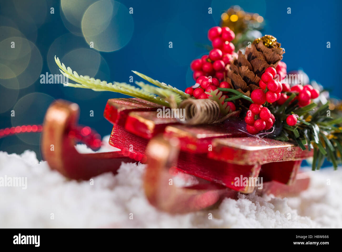 Decorative sleigh with roan-tree and christmas tree branches, driving on snow, in the background the beautiful bokech balls. Stock Photo