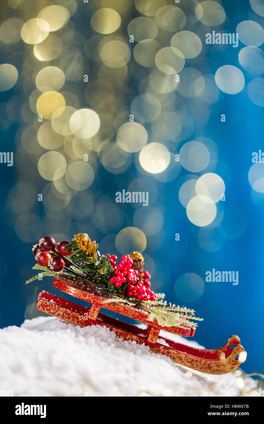 Sleigh with Christmas decoration on snow at blue background with gold glitter. Stock Photo