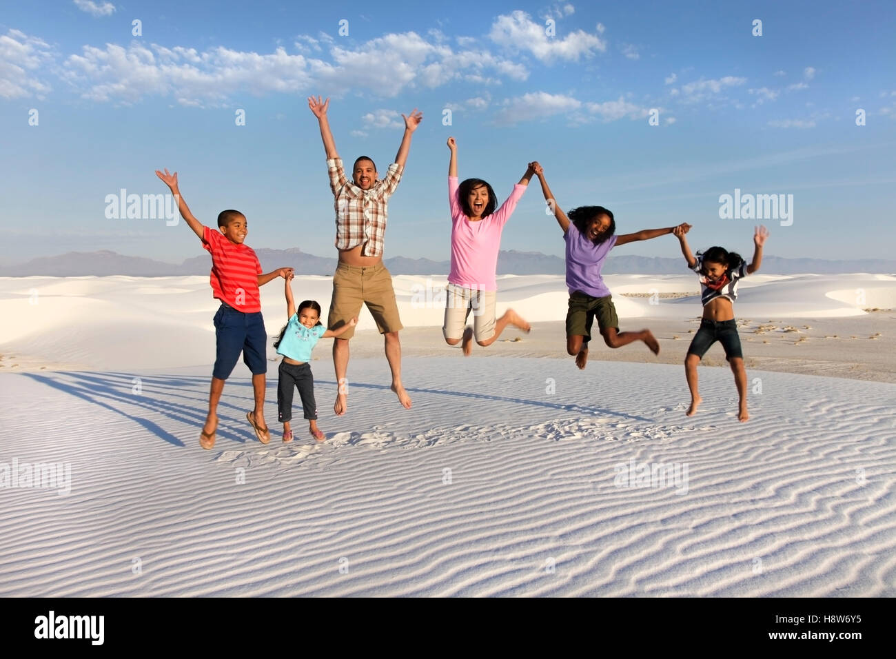 Family jumping for joy at White Sands National Park Stock Photo