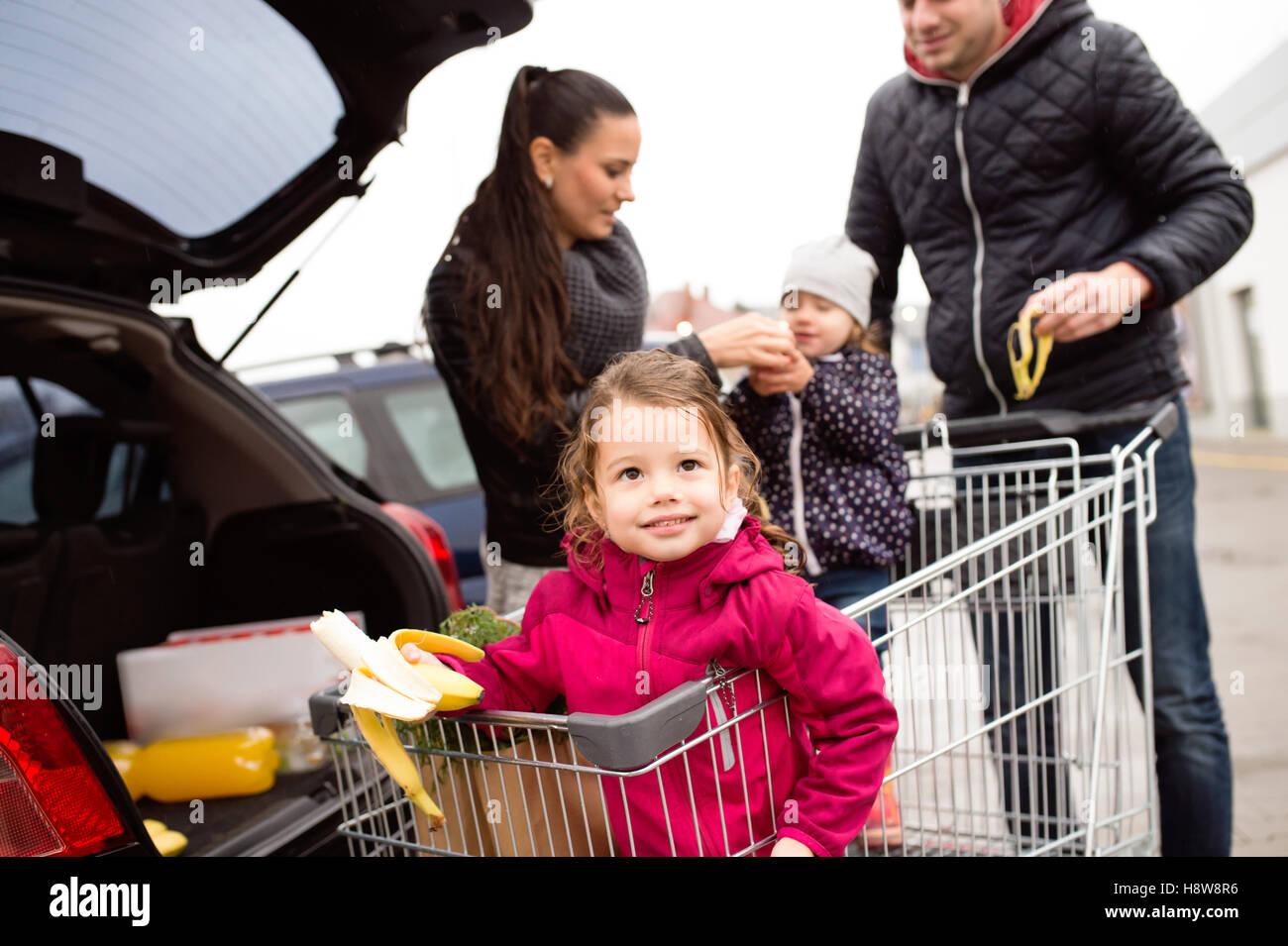 Parents pushing shopping cart with groceries and their daughters Stock ...