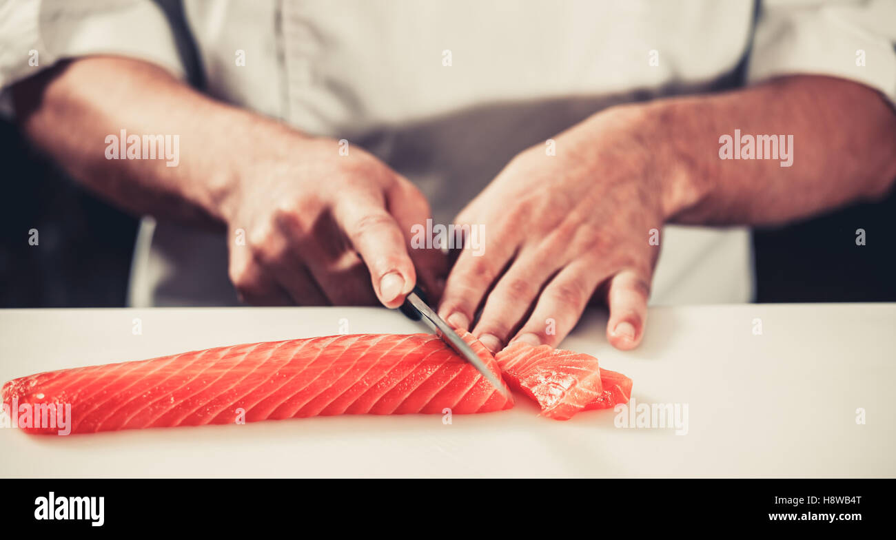 Cook cutting salmon Stock Photo