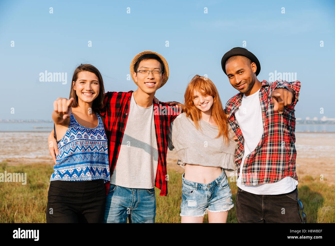 Multiethnic group of smiling young people standing together and ...