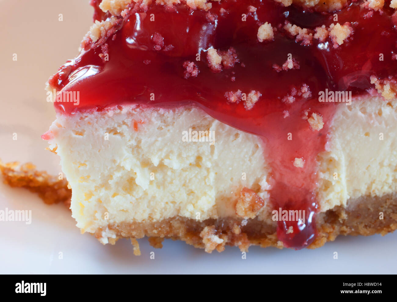 Front of a piece of cheesecake with graham cracker crust and cherry