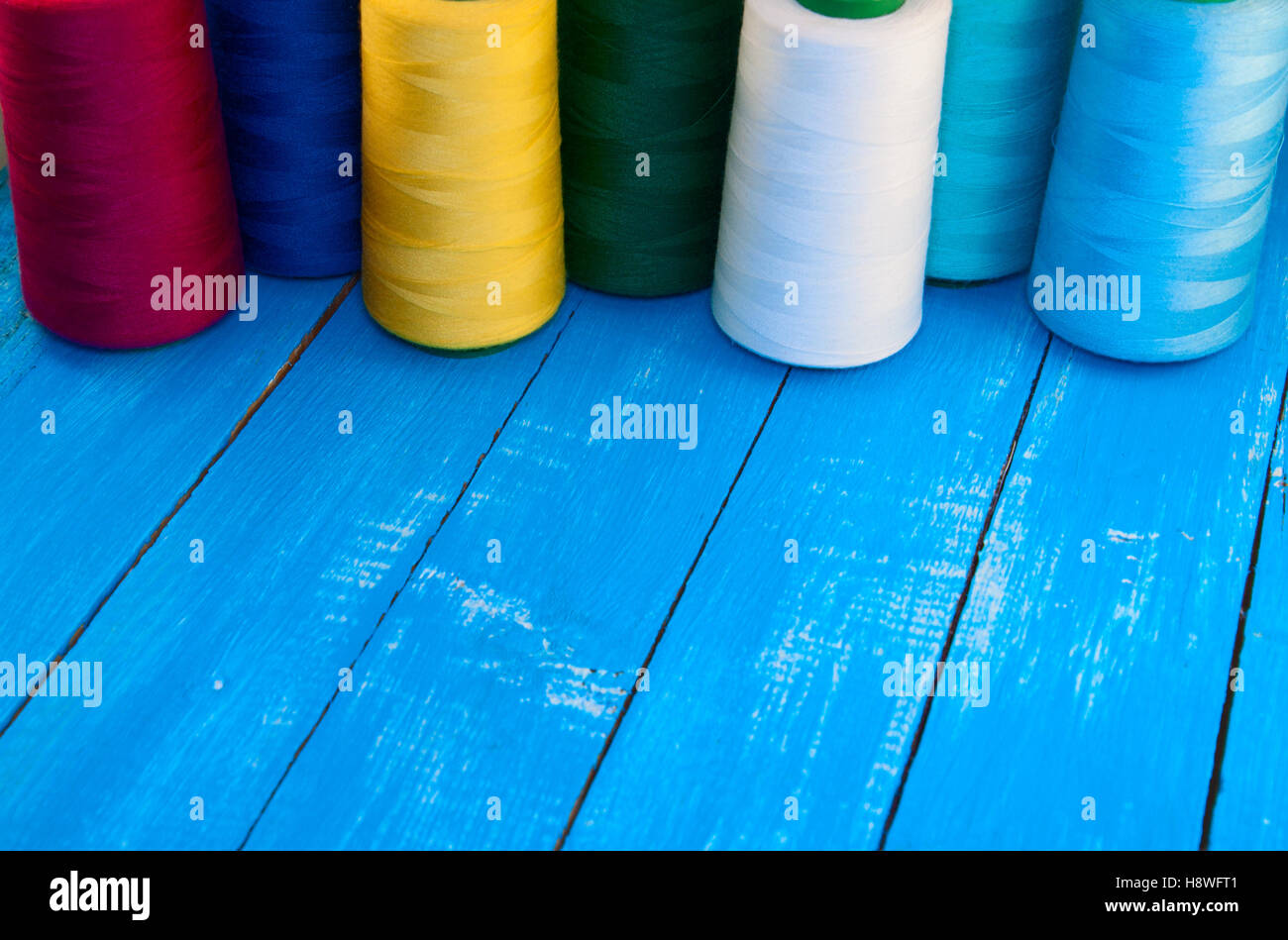 Several of colored spools of thread for sewing and embroidery on a blue ...