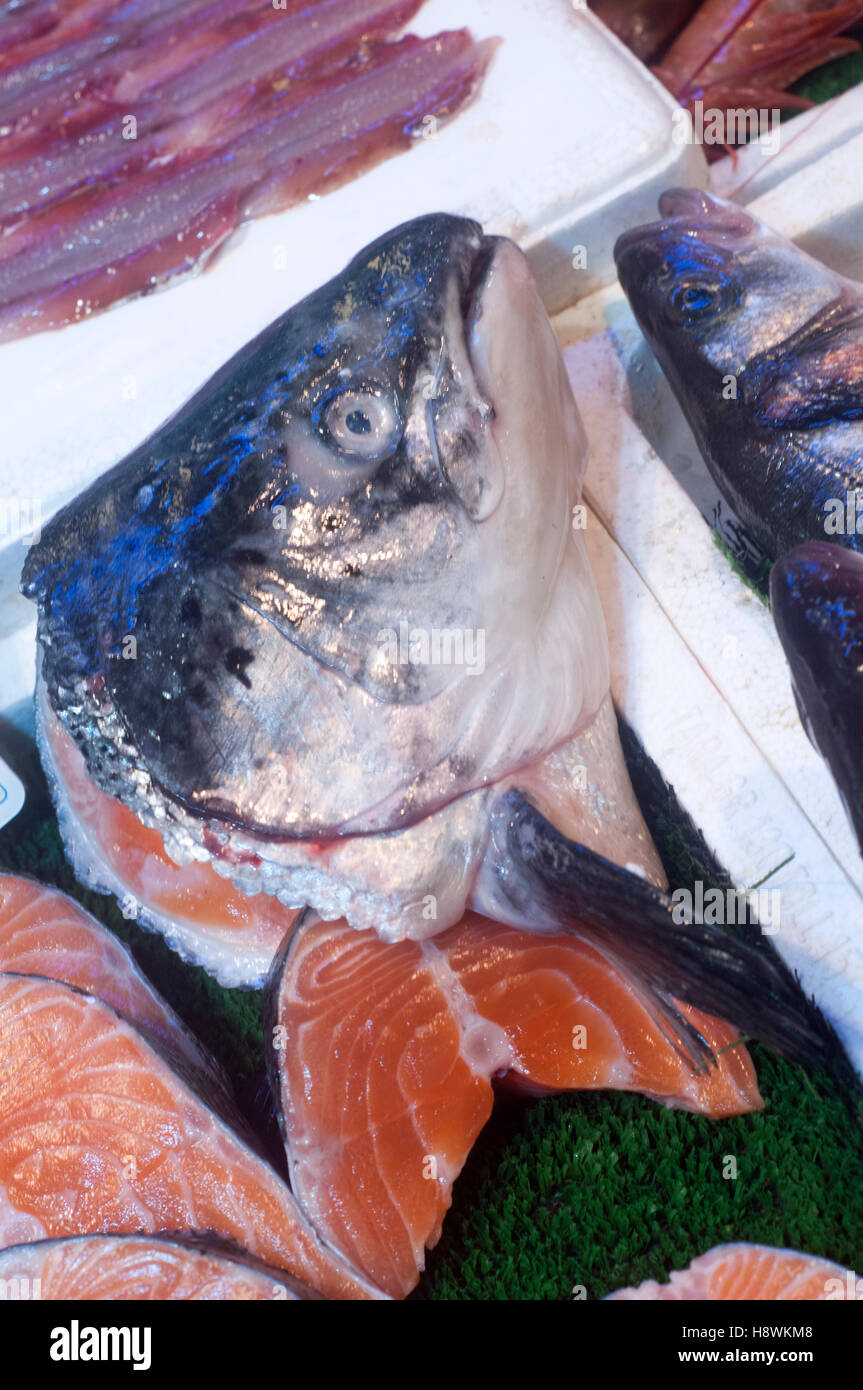Fish head on salmon steaks in white styrofoam containers on display in fish market. Stock Photo