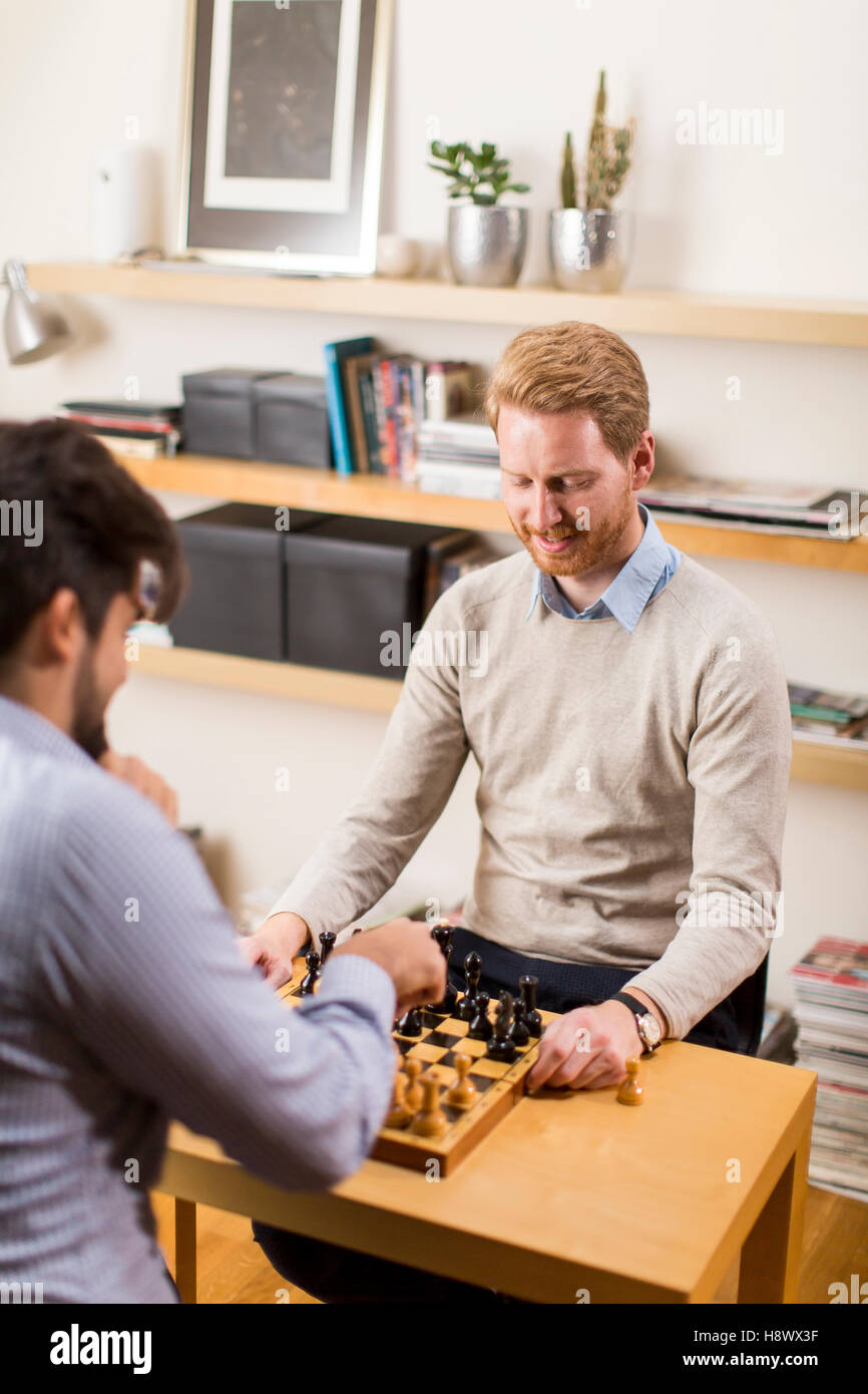 Two young men playing chess in room Stock Photo