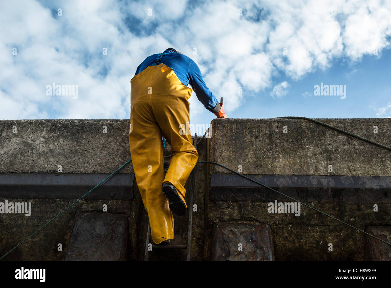 Fisherman climbing harbour steps Stock Photo