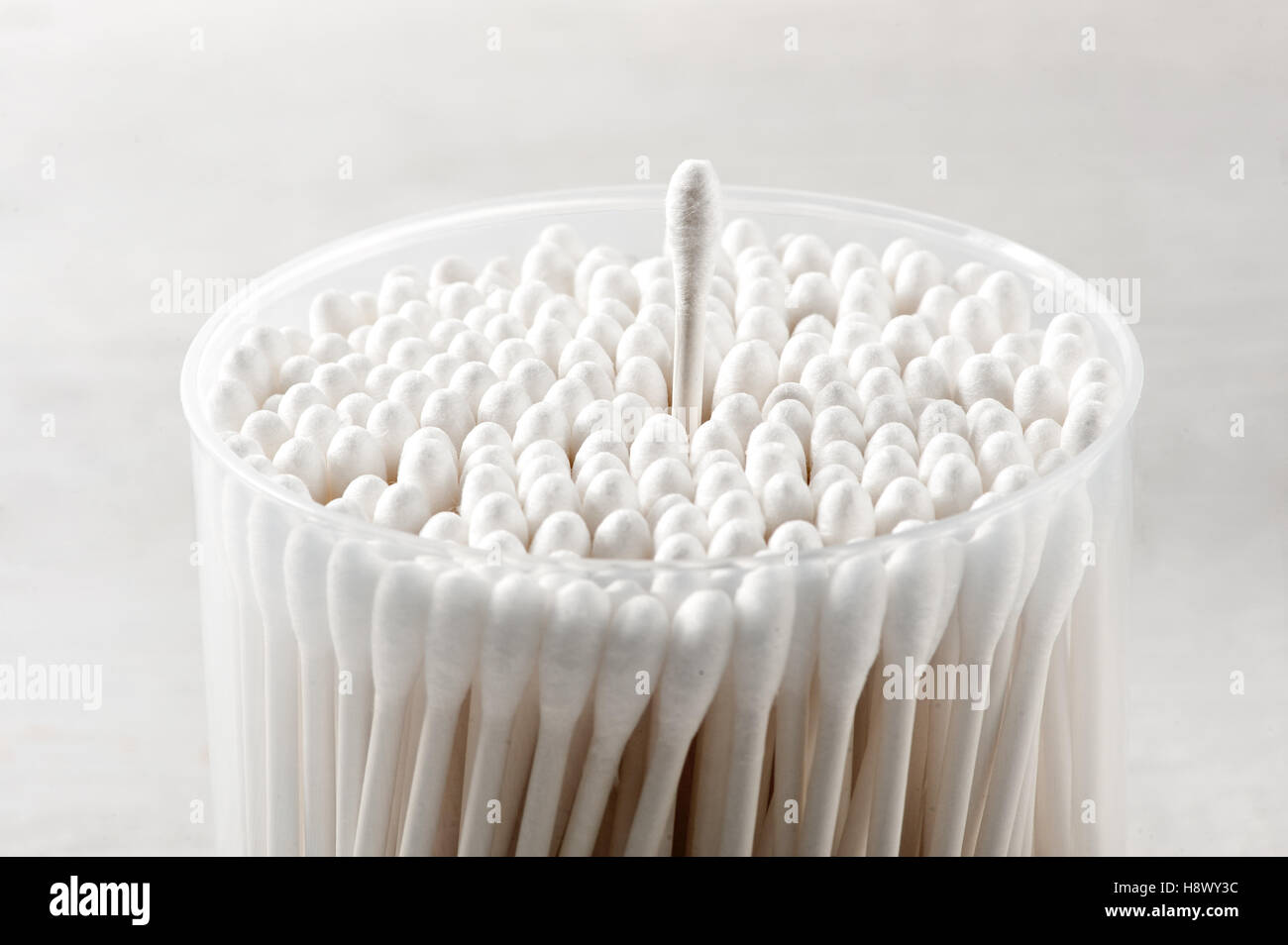Cotton buds in a plastic container with a single bud raised above the
