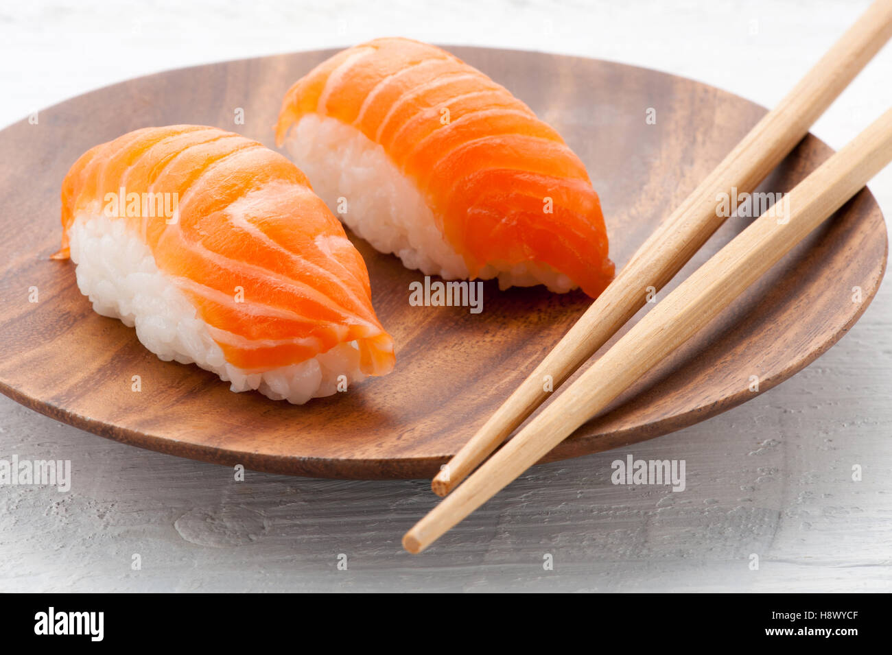 Two fresh salmon Nighiri sushi on a wooden plate with chopsticks served as an appetizer to dinner Stock Photo