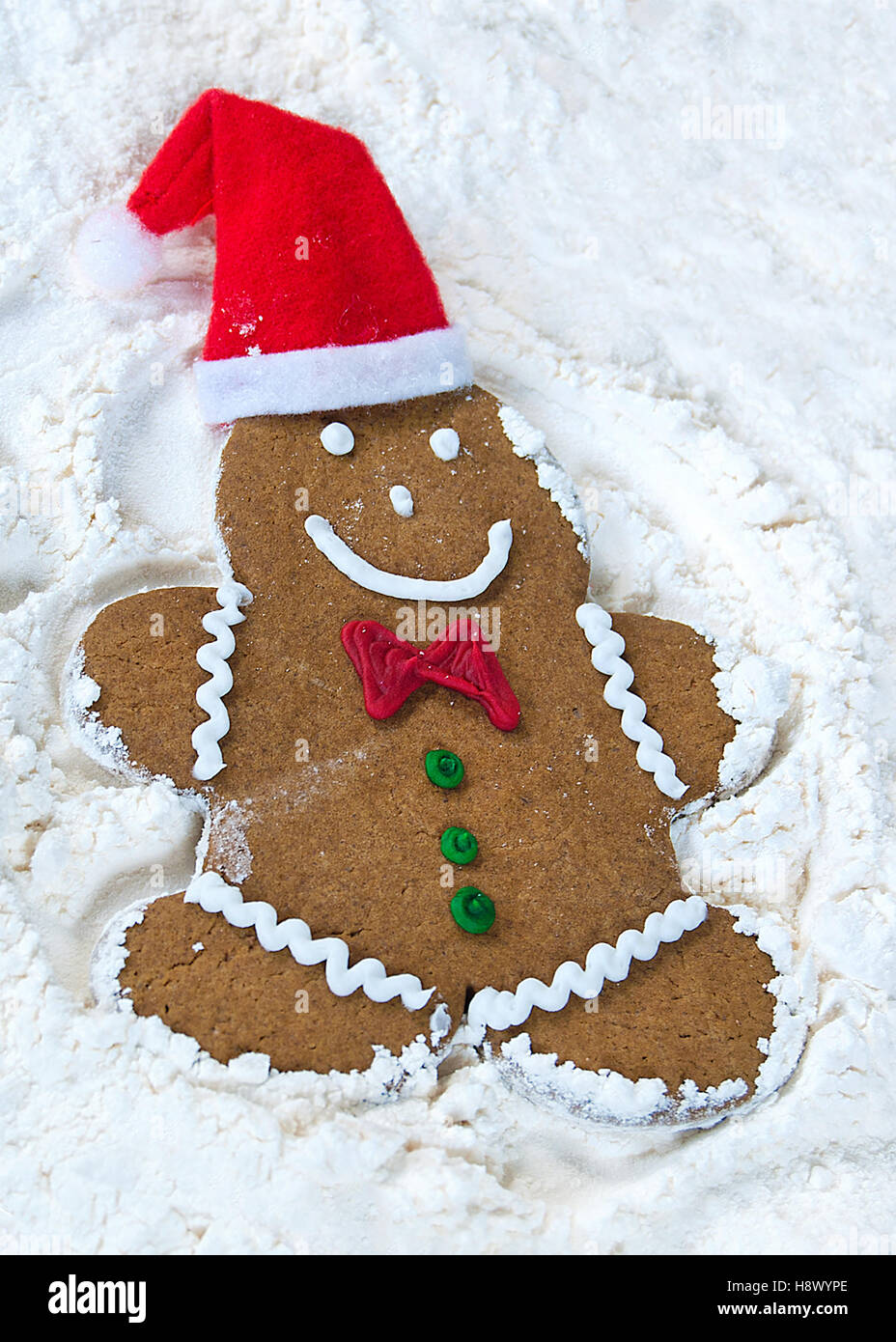 ginberbread man with Christmas hat making a snow angel in white flour Stock Photo
