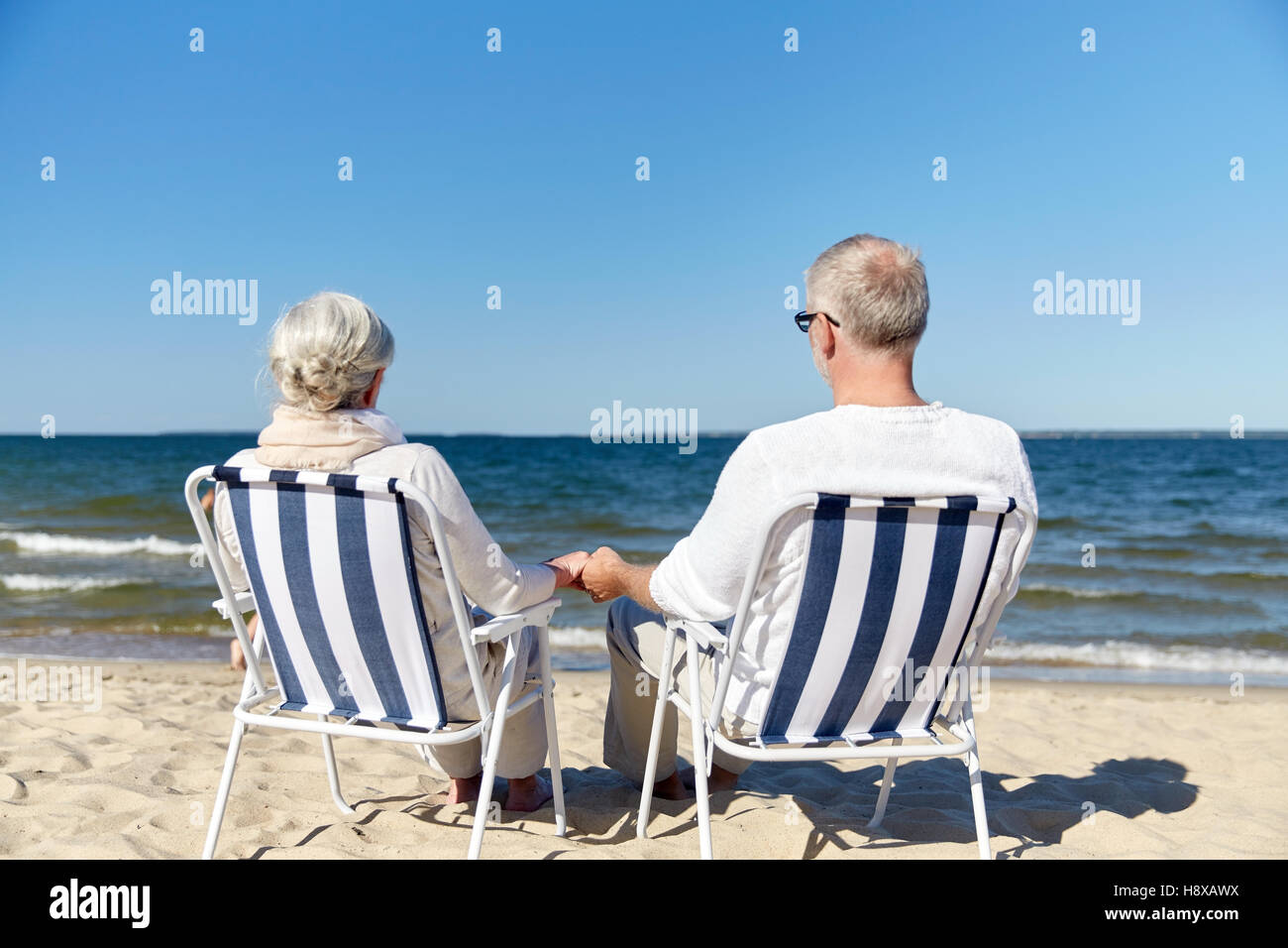 senior couple sitting on chairs at summer beach Stock Photo - Alamy