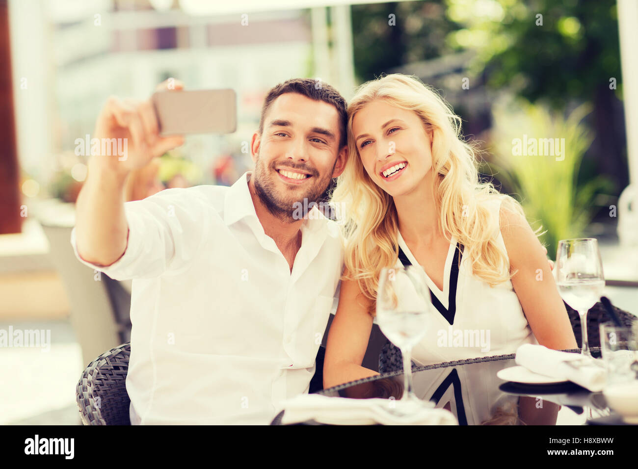 happy couple taking selfie with smatphone at cafe Stock Photo - Alamy