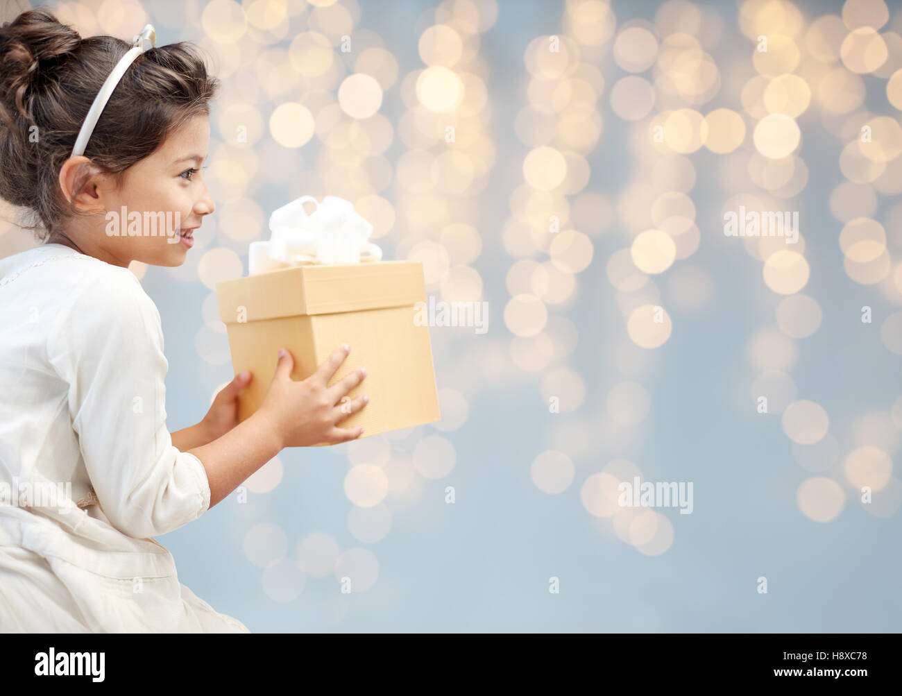 smiling little girl with gift box over lights Stock Photo - Alamy