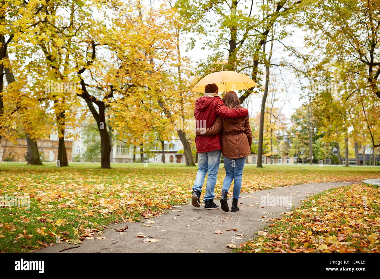 happy couple with umbrella walking in autumn park Stock Photo - Alamy