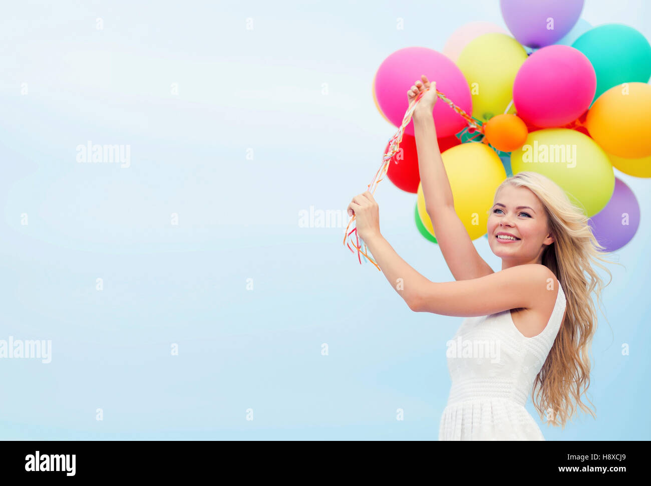 smiling woman with colorful balloons outside Stock Photo