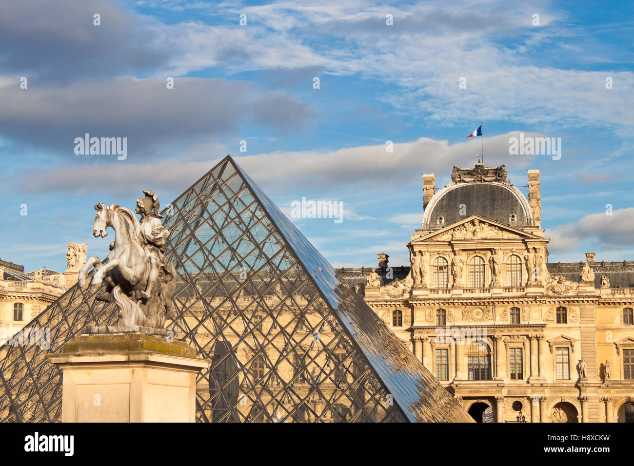 PARIS - SEPTEMBER 19, 2013: Equestrian statue of king Louis XIV in front of Louvre Palace and  the Pyramid in Paris, France. Stock Photo