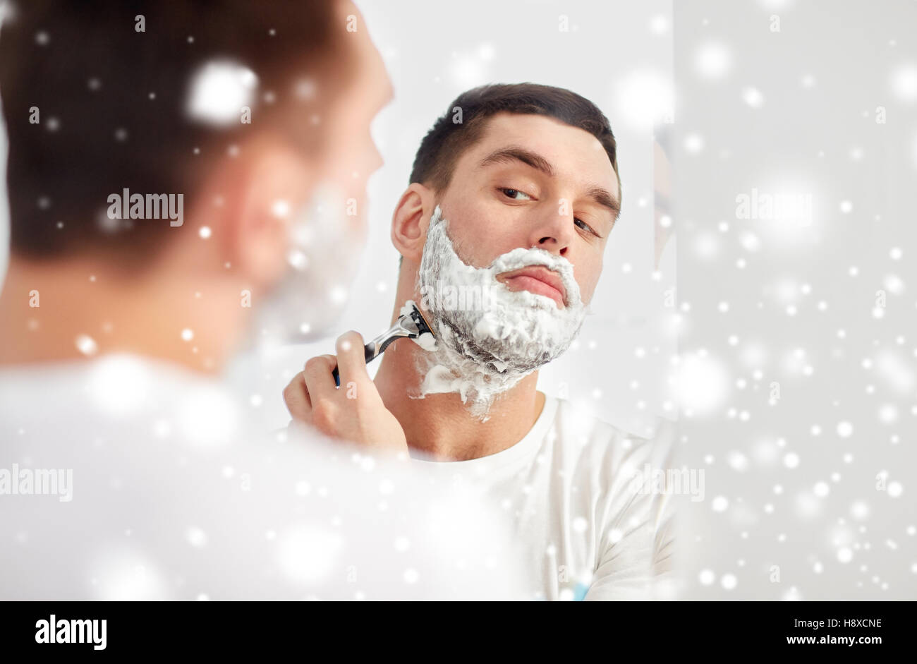 man shaving beard with razor blade at bathroom Stock Photo