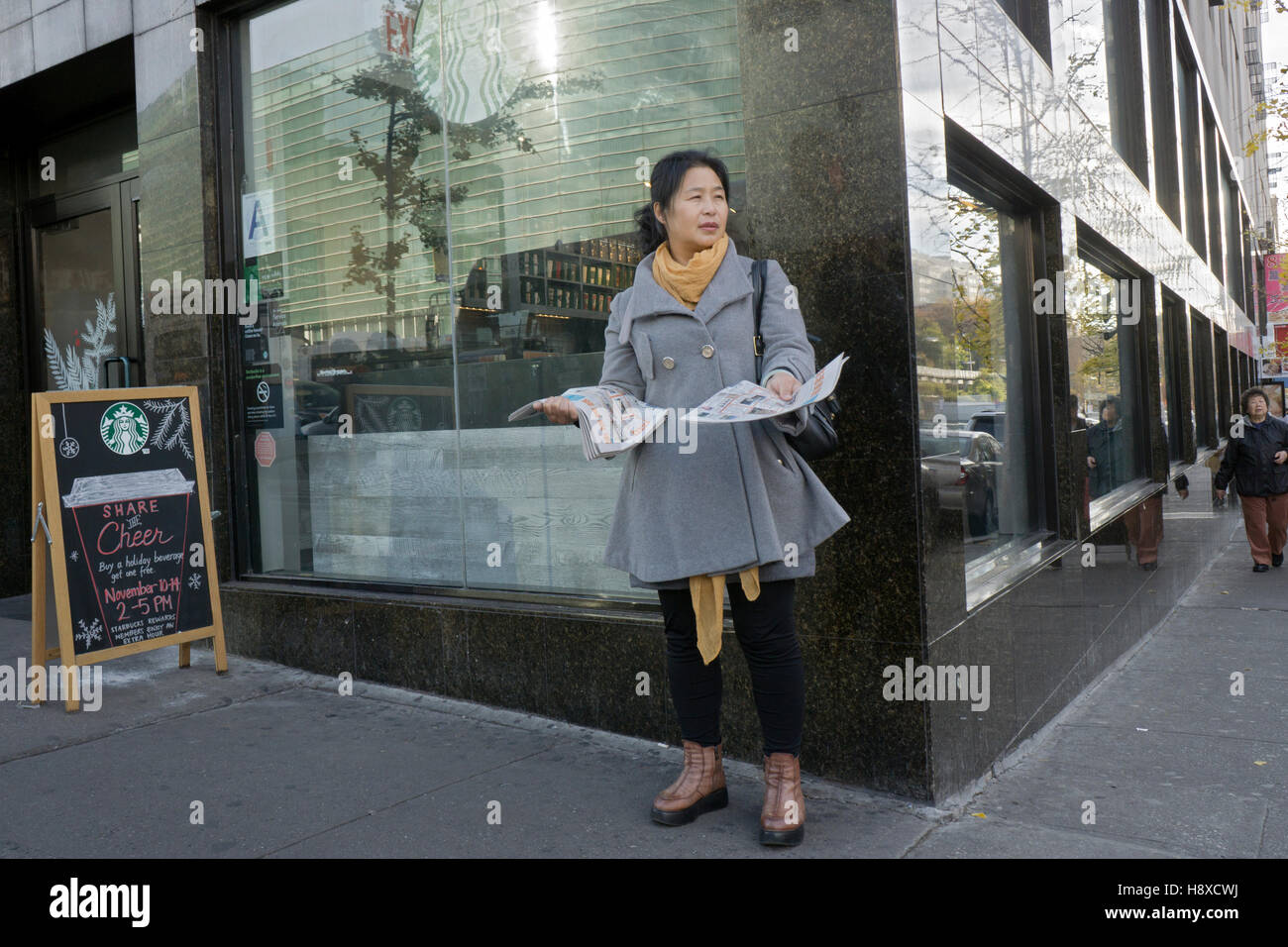 A Chinese woman handing out flyers outside Starbucks on Main Street in Chinatown, Flushing, Queens, New York City Stock Photo
