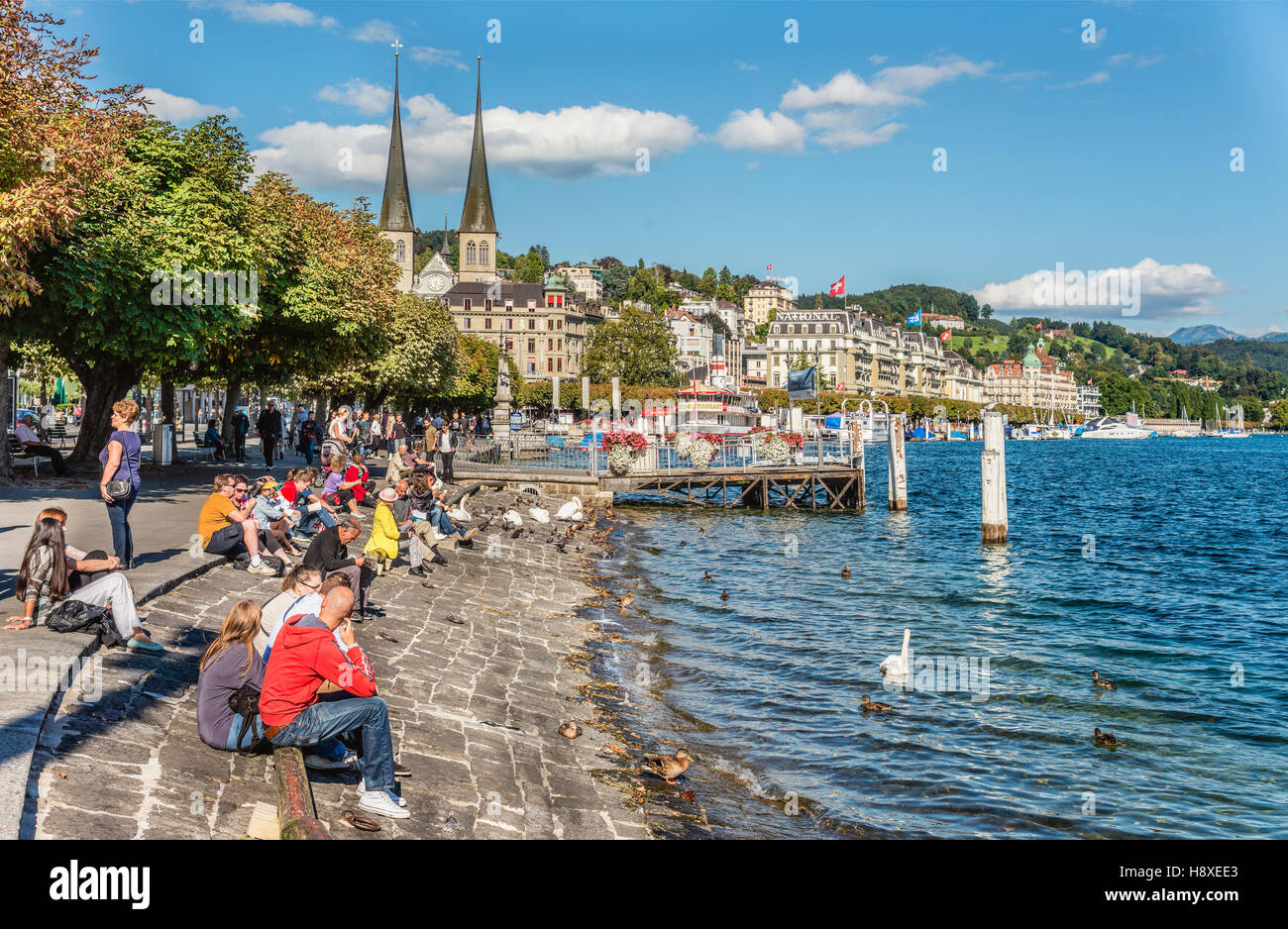 Tourists relax at the Schweizerhofquai lakeshore of Lake Lucerne in Summer, Lucerne, Switzerland Stock Photo