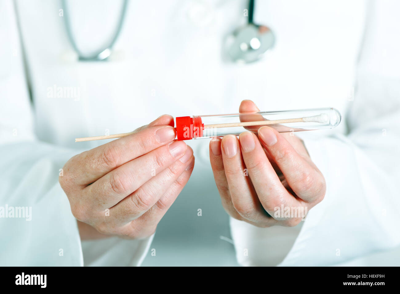 Laboratory test tube with cotton swab in scientist's hand, female